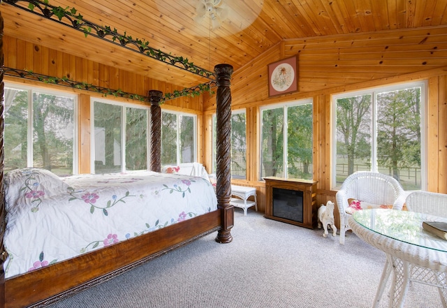 bedroom with multiple windows, wood walls, wooden ceiling, and carpet flooring