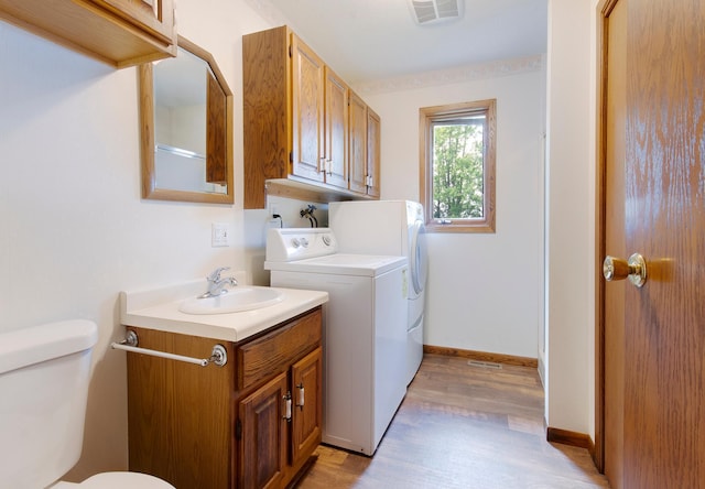 washroom featuring laundry area, light wood finished floors, visible vents, separate washer and dryer, and a sink