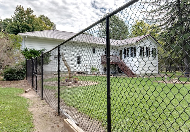 view of side of property with fence, metal roof, and a lawn