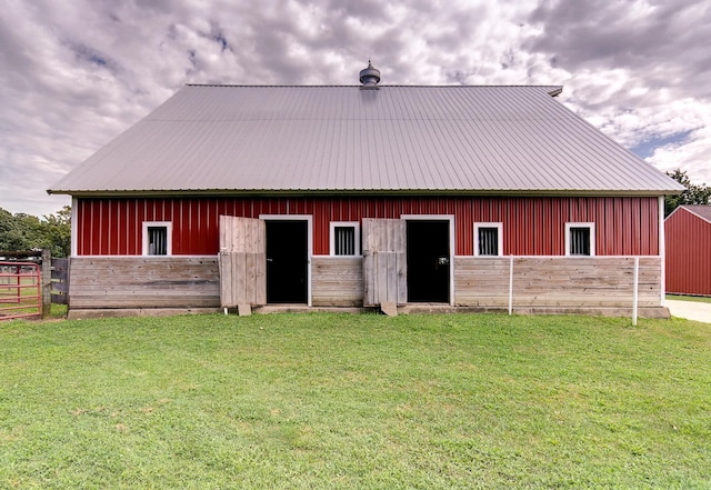 back of house featuring an exterior structure, metal roof, board and batten siding, and an outbuilding