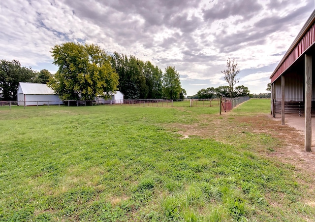 view of yard with fence, an outdoor structure, and a rural view