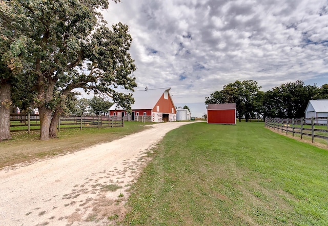 view of yard featuring an outbuilding, fence, and dirt driveway