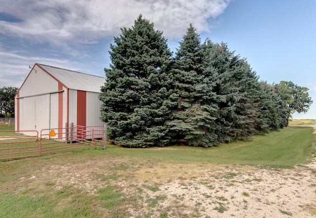 view of yard featuring a detached garage, fence, and an outbuilding