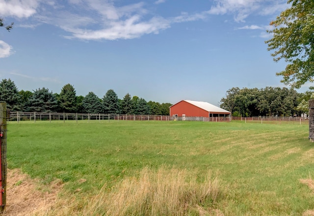 view of yard with an outbuilding, a rural view, and fence