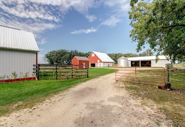 view of street featuring a rural view, a pole building, a gated entry, and driveway