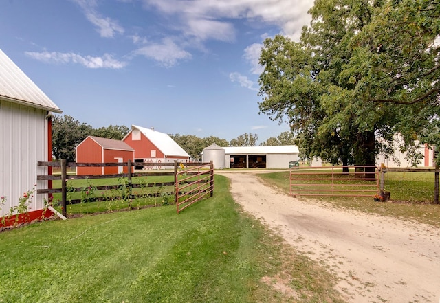 view of yard with an outbuilding, fence, a garage, a pole building, and driveway