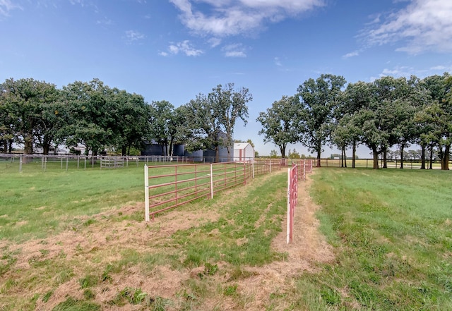 view of yard featuring an outbuilding, a rural view, and fence