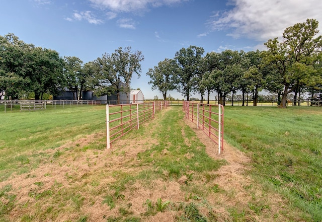 view of yard with fence, an outbuilding, and a rural view