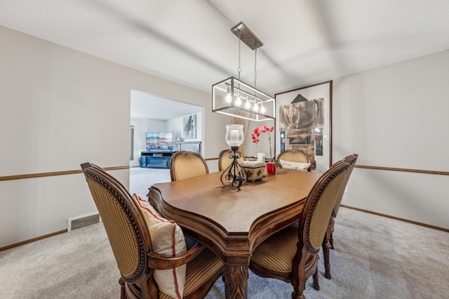 dining area with visible vents, light carpet, a textured ceiling, and baseboards