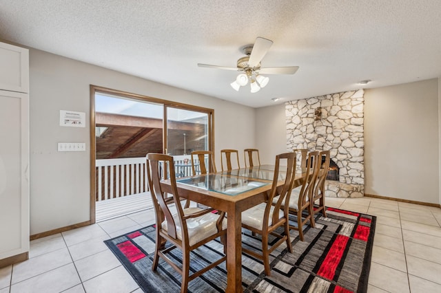 dining space with light tile patterned floors, baseboards, a ceiling fan, and a textured ceiling