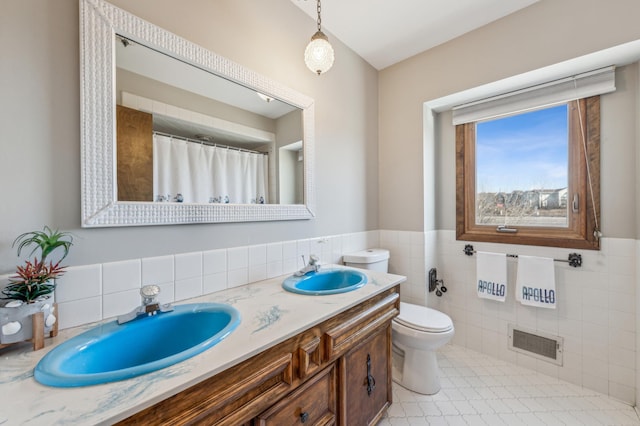 full bathroom featuring toilet, tile walls, visible vents, and a sink