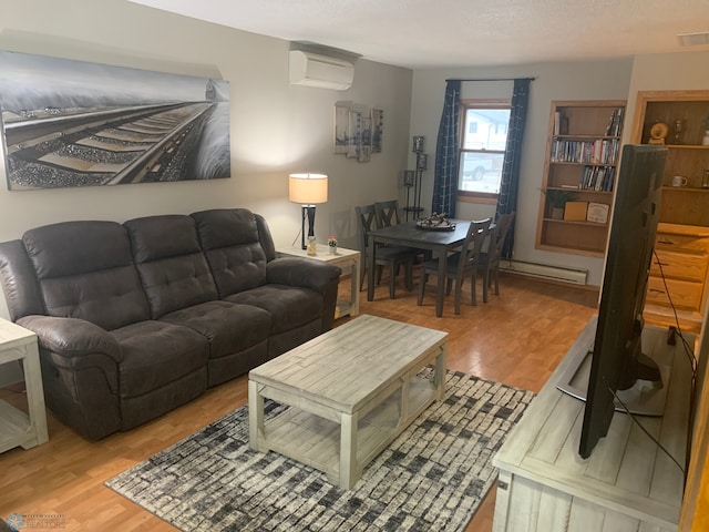 living area with an AC wall unit, visible vents, baseboard heating, and wood finished floors