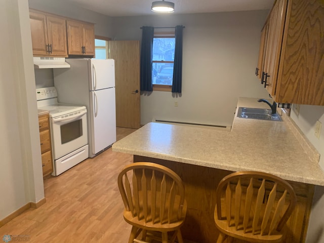 kitchen featuring under cabinet range hood, a baseboard heating unit, a peninsula, white appliances, and a sink