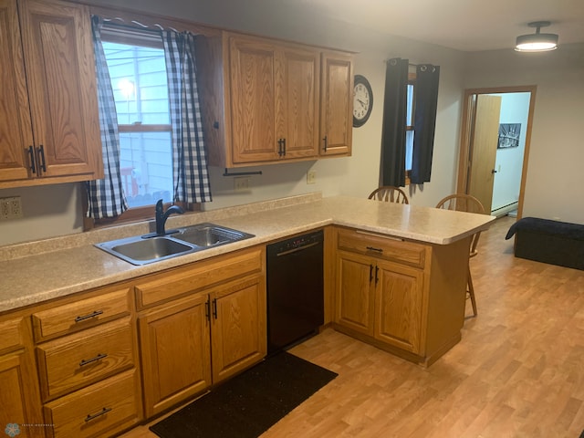 kitchen featuring light wood-style floors, a sink, dishwasher, a peninsula, and a kitchen bar