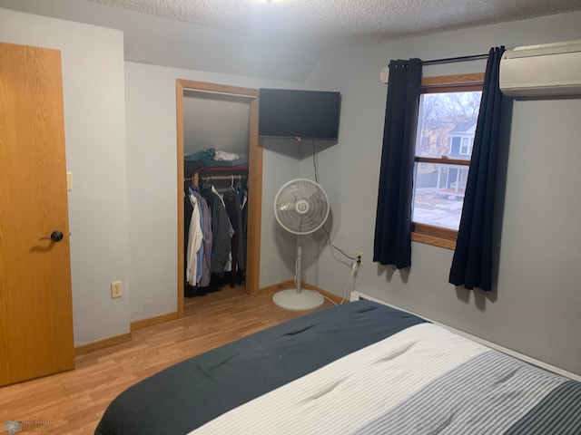 bedroom featuring a closet, a textured ceiling, baseboards, and wood finished floors