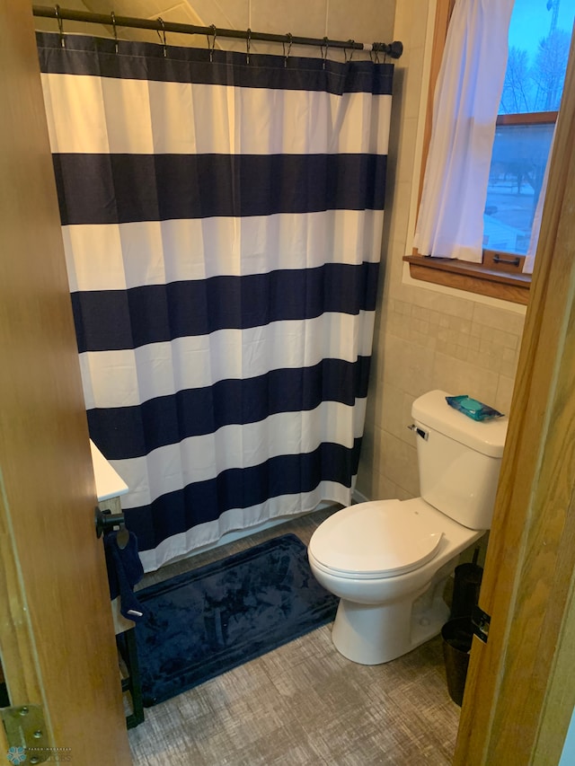 full bath with a shower with curtain, toilet, and tile walls