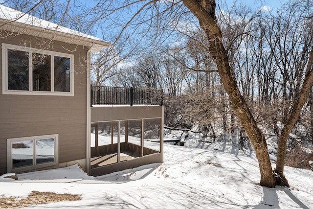 yard layered in snow featuring a sunroom