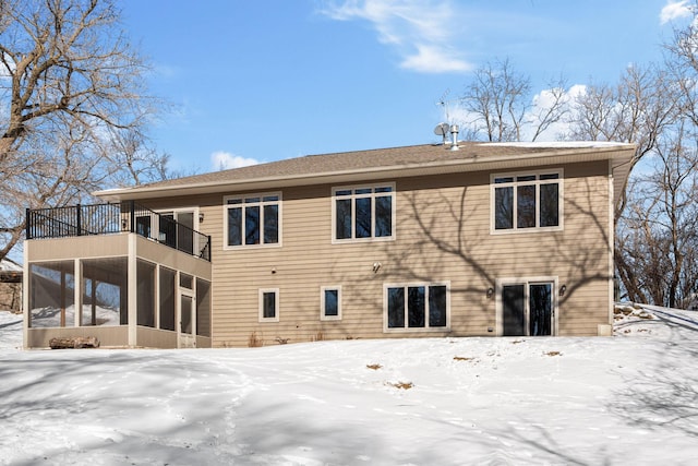 snow covered property with a balcony and a sunroom