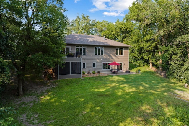 rear view of house with a sunroom, a yard, a balcony, and a patio