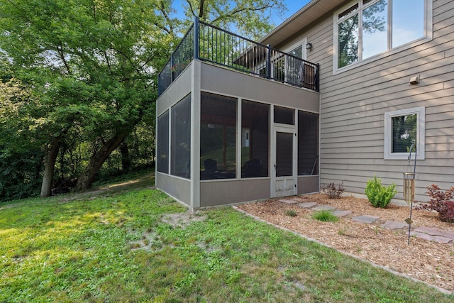 back of property featuring a lawn, a balcony, and a sunroom