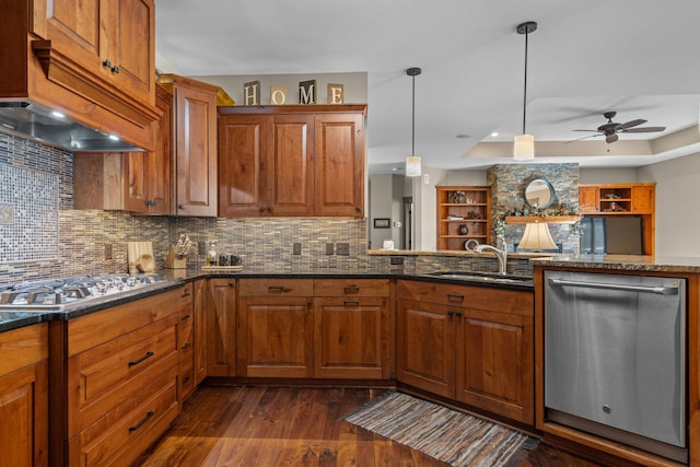 kitchen featuring brown cabinetry, a tray ceiling, stainless steel appliances, and a sink