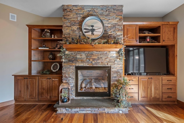 unfurnished living room with visible vents, a fireplace, baseboards, and wood finished floors