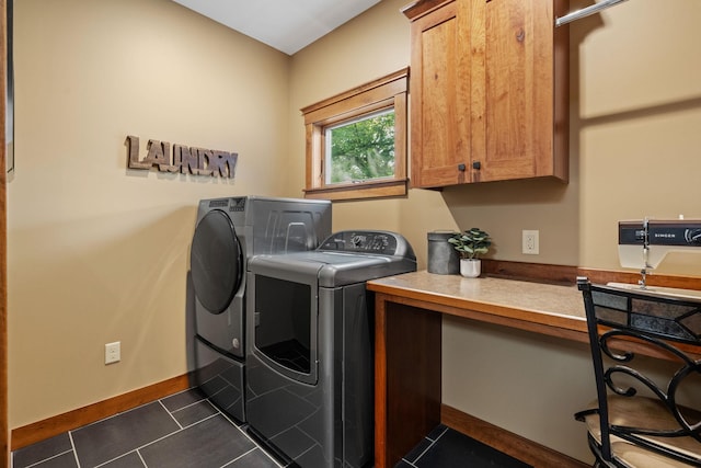 clothes washing area with dark tile patterned flooring, washing machine and dryer, cabinet space, and baseboards