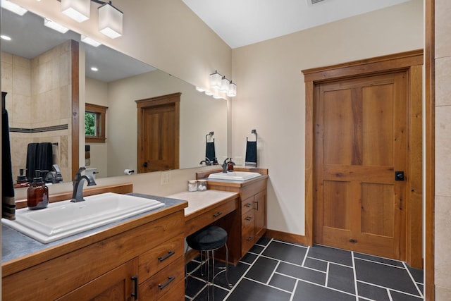 full bath with tile patterned flooring, a sink, baseboards, and double vanity