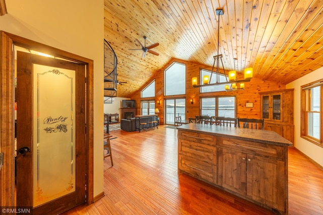 kitchen with high vaulted ceiling, wooden ceiling, a center island, light wood finished floors, and dark countertops