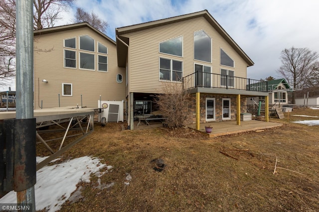 rear view of house with a deck, stone siding, and a patio area