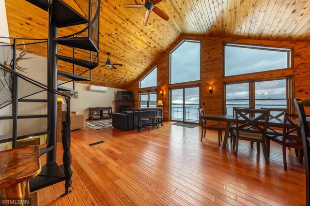 living area featuring ceiling fan, high vaulted ceiling, wood walls, wooden ceiling, and hardwood / wood-style flooring