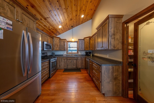 kitchen featuring appliances with stainless steel finishes, a sink, vaulted ceiling, wooden ceiling, and wood-type flooring