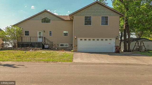 view of front facade with driveway, an attached garage, and a front lawn
