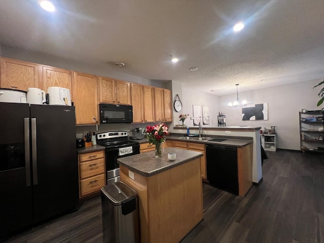 kitchen featuring a peninsula, a sink, dark wood-style floors, black appliances, and dark countertops