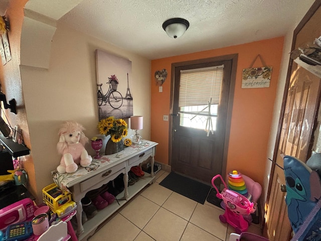 doorway to outside with a textured ceiling and light tile patterned flooring