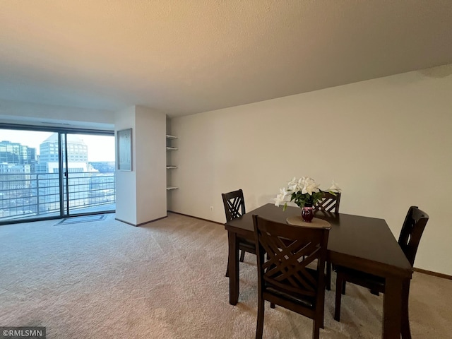 dining area featuring baseboards, light carpet, and a textured ceiling