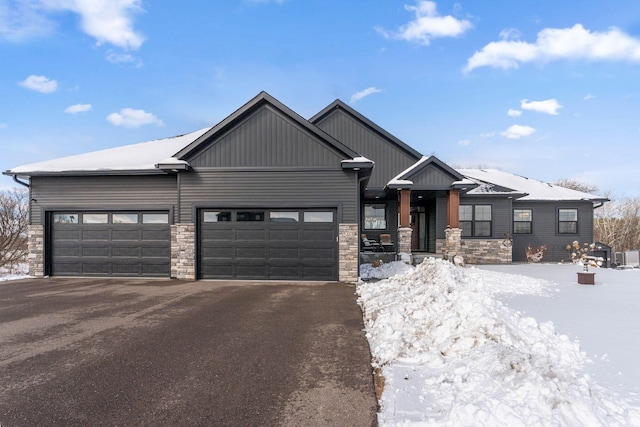 view of front of house with a garage, stone siding, and driveway