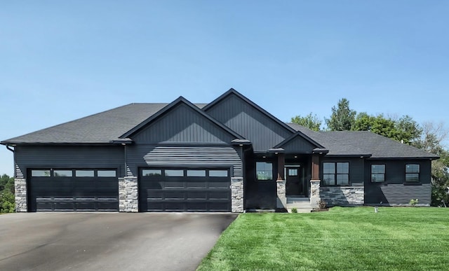 view of front facade with stone siding, a garage, driveway, and a front yard