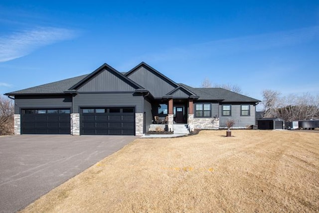 view of front of home with a garage, stone siding, and aphalt driveway