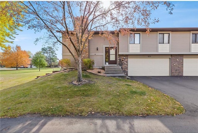 view of front of home with driveway, an attached garage, a front lawn, and brick siding