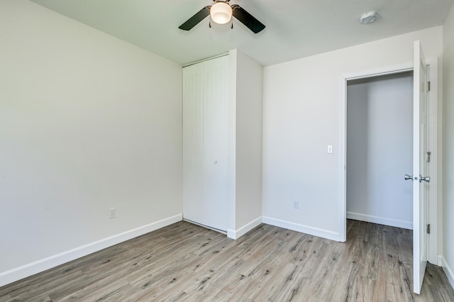 unfurnished bedroom with a ceiling fan, a closet, baseboards, and wood finished floors