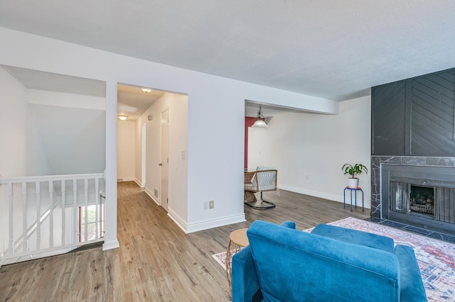 living room with a large fireplace, wood finished floors, and baseboards