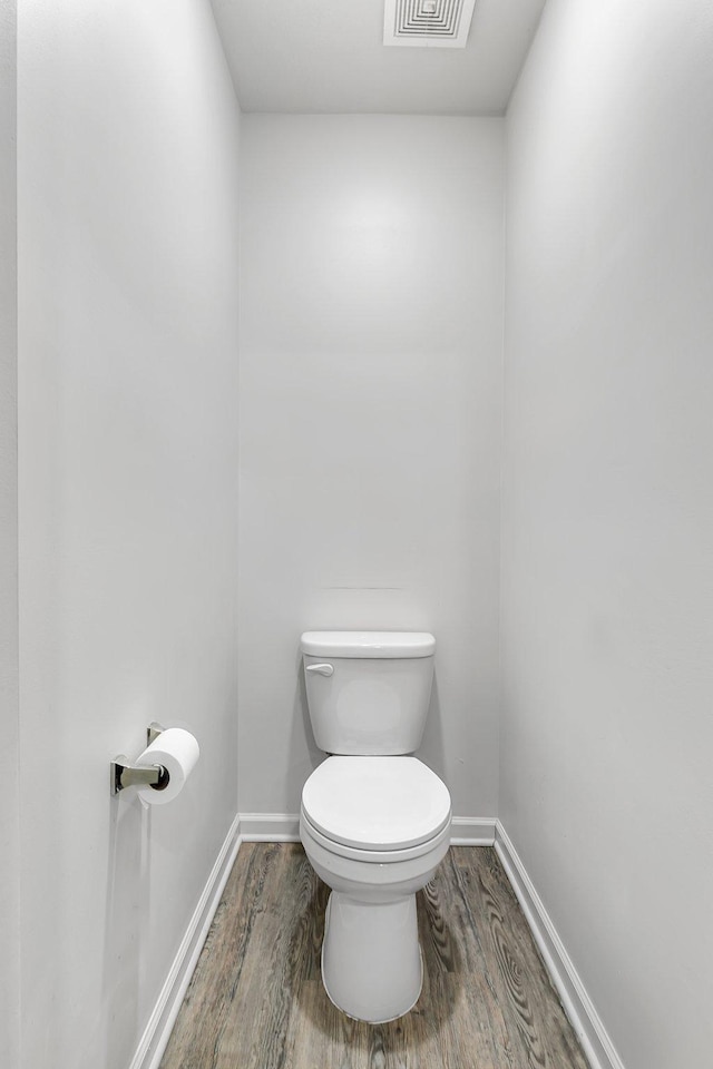 bathroom featuring toilet, baseboards, and wood finished floors