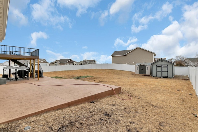 view of yard featuring a storage shed, a patio, a fenced backyard, stairway, and an outbuilding