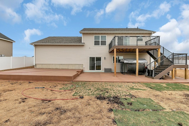 back of property with a hot tub, stairs, fence, a wooden deck, and a patio area