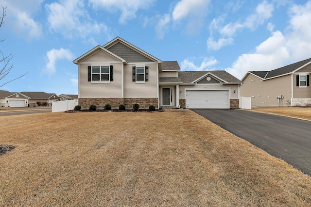 view of front of house with aphalt driveway, a front yard, fence, a garage, and stone siding