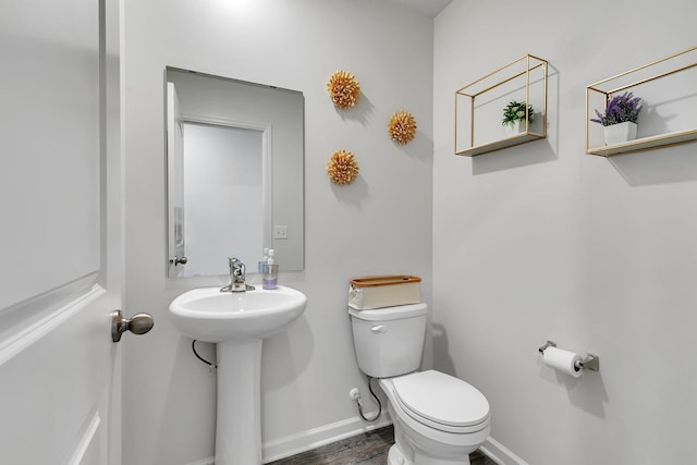 bathroom with wood finished floors, a sink, toilet, and baseboards