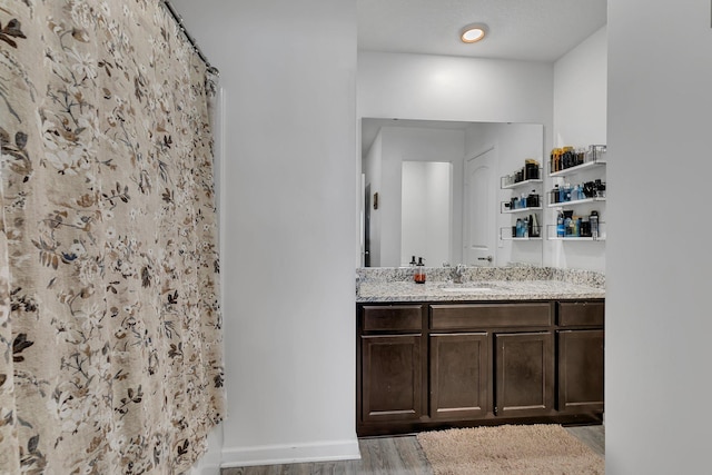 bathroom with baseboards, wood finished floors, vanity, and a shower with curtain