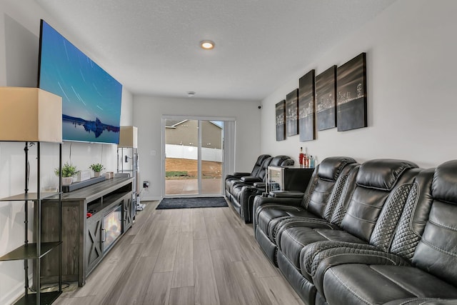 living room featuring a textured ceiling, wood finished floors, and baseboards