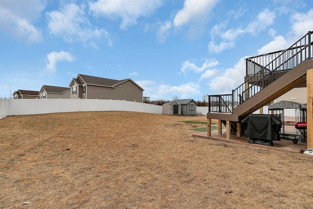 view of yard featuring an outbuilding, a gazebo, a storage shed, fence, and stairs